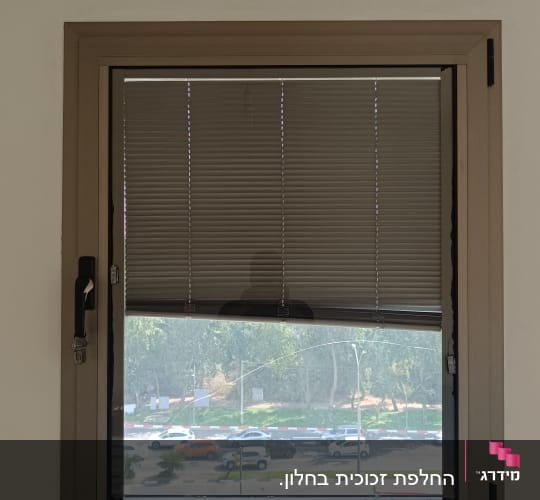 תריסים סגורים למחצה על חלון עם מסגרת עץ